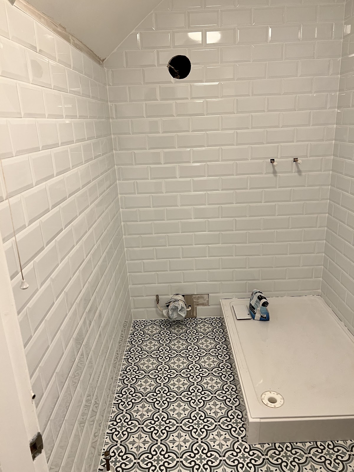 Bathroom in progress with white bevelled metro tile and patterned floor