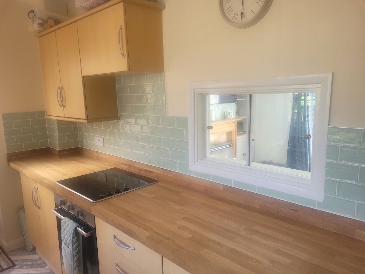 Sage-green metro tile splashback with oak worktop